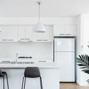 沃纳姆堡Timor Street Apartments的厨房配有白色橱柜、冰箱和椅子