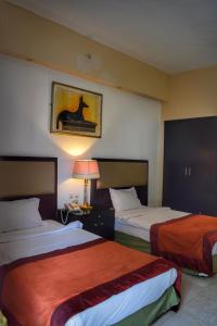 沙姆沙伊赫Desert View Sharm Hotel的酒店客房,设有两张床和一盏灯