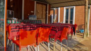 锡吉里亚Pidurangala Hostel的一张桌子,上面摆放着橙色椅子,还有红黑色的桌布