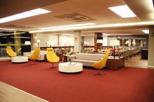 戈亚尼亚Strassen Hotel的图书馆设有黄色椅子、沙发和桌子