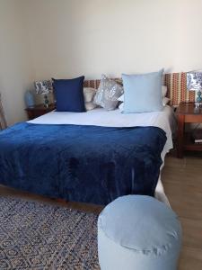 惠灵顿Lady Loch Country House的一间卧室配有一张带蓝色毯子和凳子的床