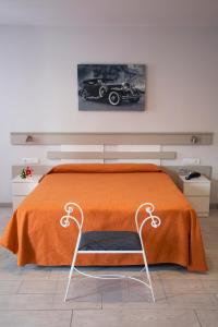 卡里拉Apartamentos Comfort Calella的一间卧室配有一张带橙色毯子和椅子的床