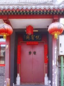 北京Beijing Yue Bin Ge Courtyard Hotel的红色的大门,有两盏红色灯笼的建筑物
