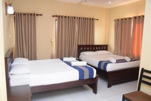 贾夫纳PJ Hotels Jaffna的配有窗帘的酒店客房内的两张床