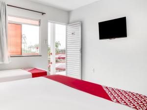 ParipeOYO Praia Hotel Recanto do Tomé - Salvador的一间白色卧室,配有两张床和一台平面电视