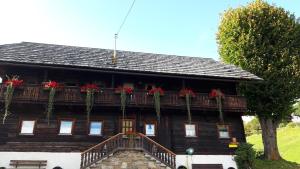 FresachPension Barzaunerhof的阳台上的木房子,种有红色的鲜花