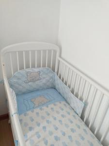 Água de AltoCasa da Rosarinha的白色的婴儿床,上面有蓝色的毯子