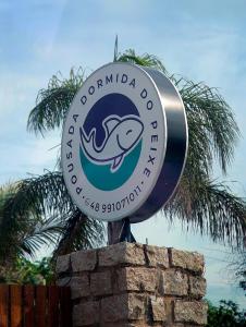 普腊亚罗萨Pousada Dormida do Peixe的石墙顶上的海豚俱乐部标志
