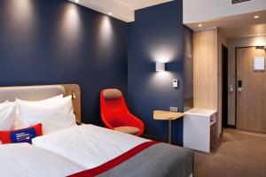 达姆施塔特Holiday Inn Express - Darmstadt, an IHG Hotel的酒店客房,配有一张床和一张红色椅子