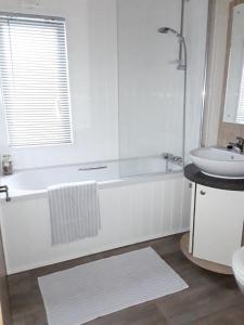 PoundstockClearwater Lodge Bude的白色的浴室设有浴缸和水槽。