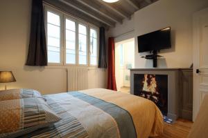 埃特勒塔Au bonheur d'Etretat的一间卧室配有一张带壁炉和电视的床。