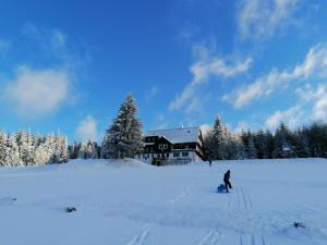贝内茨科chata Karolínka的一个人在房子前面的雪中滑雪