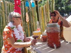 凯里凯里The Luxury Honolulu with Private Bar at Paradise Valley Glamping的两个女人坐在桌子上,拿着一罐液体