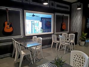 巴东马士力Dorm Master的餐厅墙上设有桌椅和吉他