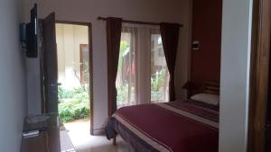 日惹日惹阿罗哈酒店的一间卧室设有一张床和一个大窗户
