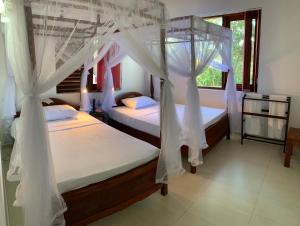 佩勒代尼耶Lotus Villa Kandy的卧室内的两张床,带白色窗帘