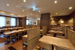 富士市露樱酒店 新富士站南(Hotel Route Inn Shinfuji Ekiminami)的用餐室配有木桌和椅子