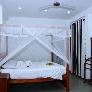 坦加拉Little Sunshine Guest House & Restaurant的卧室配有带白色床单的天蓬床