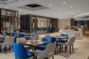 迪拜Hyatt Place Dubai Jumeirah的一间设有蓝色桌椅的餐厅和一间酒吧