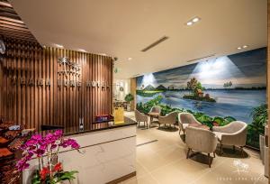 胡志明市Thanh Long Hotel - Bach Dang的一间设有椅子和墙上一幅画的等候室