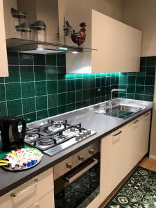 阿雷佐Appartamento Mariapaola的厨房配有炉灶、水槽和绿色瓷砖