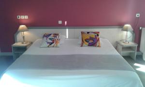 普尔德勒济克Hotel Restaurant Le Capricorne的一间卧室配有一张带两盏灯的大型白色床。