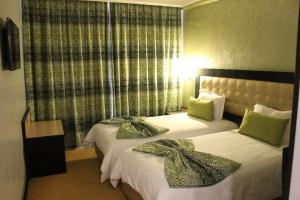 卡萨布兰卡阿尔瓦利德酒店的酒店的客房 - 带两张带绿色枕头的床