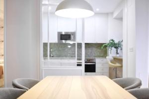 伦特里亚Apartment Alaitz Rentería的白色的厨房配有木桌和椅子