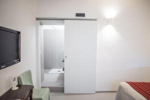 锡拉库扎阿里特斯瓦坎兹住宿加早餐酒店的一间设有一扇门的房间,配有电视和一张床