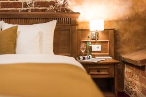 施特拉尔松德施特拉尔松斯科勒霍夫浪漫酒店的一间卧室配有一张床和一张带台灯的桌子