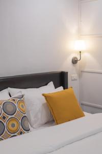 清迈The Mellow Pillow Hotel @ Chiang Mai Gate的一张带白色和黄色枕头的床和一盏灯