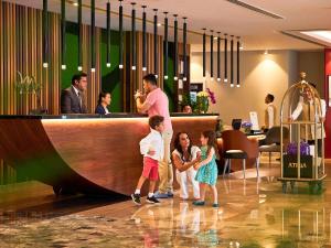 迪拜迪拜巴沙海兹美居公寓式酒店的站在酒吧前的男人和两个孩子