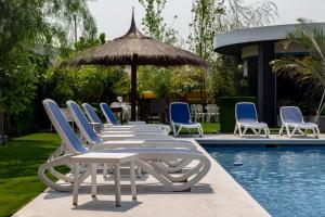 亚松森Hotel Los Alpes Cipreses的游泳池旁的一排躺椅和遮阳伞