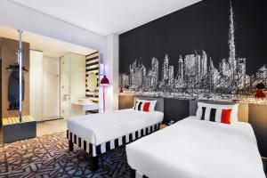 迪拜宜必思尚品迪拜机场酒店的酒店客房设有两张床,墙上挂有绘画作品