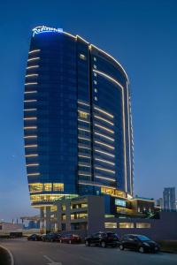 迪拜Radisson Blu Hotel, Dubai Canal View的一座大型建筑,前面有汽车停放