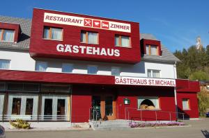 上施泰尔马克地区圣米夏埃尔Gästehaus St.Michael的一座红色和白色的建筑,设有格施塔茨餐厅