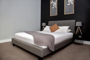TemoraRevive Central Apartments的一间卧室配有带白色床单和棕色枕头的床。