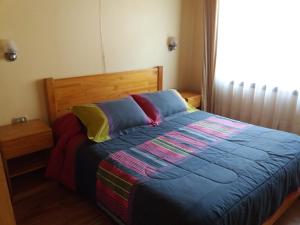 巴拉斯港Cabañas Amancay的一间卧室配有一张带彩色床单的床和一扇窗户。