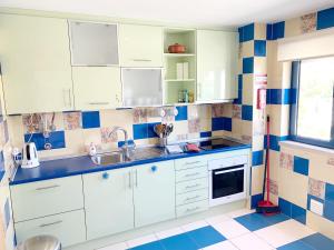 阿尔布费拉Apartamento Orada HotTub Billiard & Pool view的厨房配有白色橱柜和蓝色及白色瓷砖