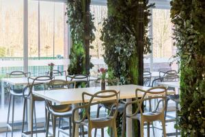 圣阿芒莱索Sure Hotel by Best Western Saint-Amand-Les-Eaux的植物丛中的一排桌椅