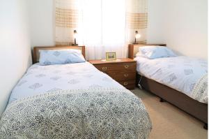 布罗肯希尔卡朋度假屋的一间卧室设有两张床、一张桌子和一个窗口。
