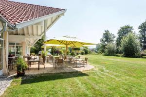 奥托博伊伦Best Western Plus Parkhotel Maximilian Ottobeuren的庭院配有桌椅和黄色雨伞。