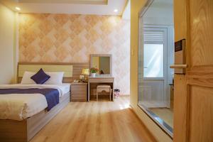 大叻Khanh Uyen 1 Hotel的一间卧室配有一张床、一张书桌和一面镜子