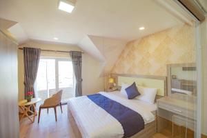 大叻Khanh Uyen 1 Hotel的一间卧室配有一张床、一张书桌和一个窗户。