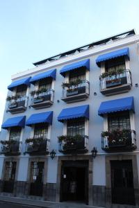普埃布拉Hotel Diana的白色的建筑,设有蓝色的遮阳篷和阳台