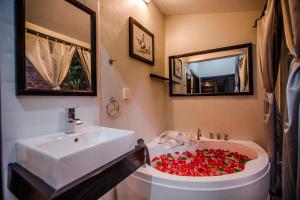 马德望马德望保护区别墅的浴室设有水槽和装满红玫瑰的浴缸。