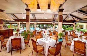 麦克坦康斯特白拉热带海滩度假村的一间带白色桌椅的餐厅和一个游泳池