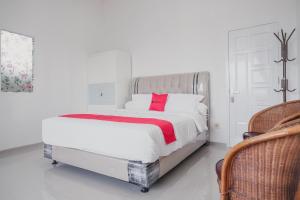 占碑市RedDoorz Syariah near Arafah Hospital Jambi的白色卧室配有一张带红色枕头的大床