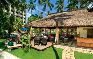 麦克坦康斯特白拉热带海滩度假村的一间带桌椅和茅草屋顶的餐厅