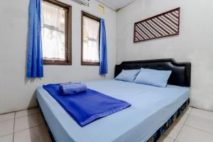 SalakanHomestay Damandiri Prambanan Syariah的一间卧室配有一张带蓝色床单和窗户的床。